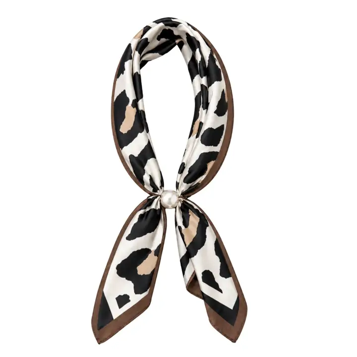 Black-and-white cow-print scarf necklace with a pearl closure, displayed against a white background.