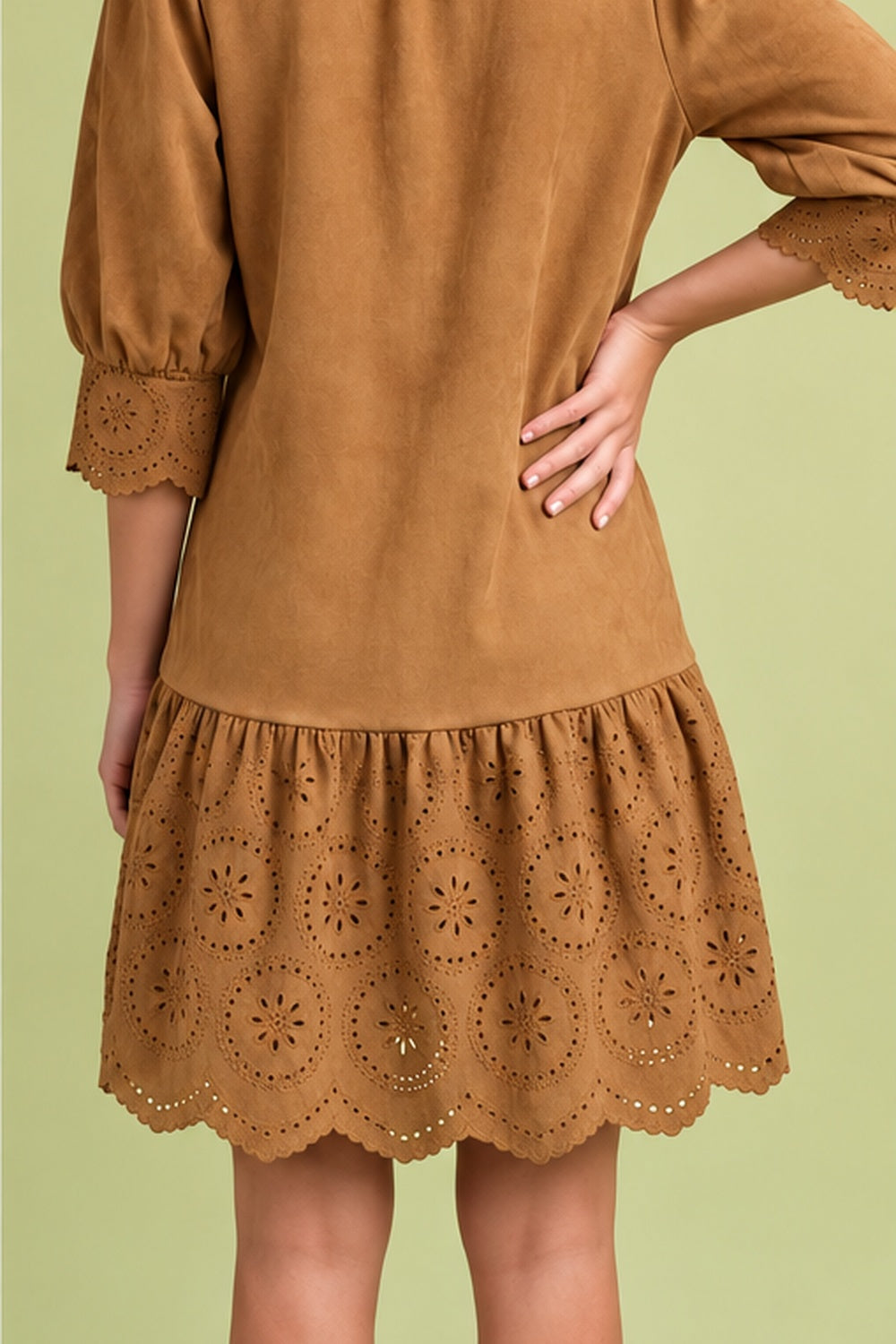 Back view of camel suede-look dress showing relaxed silhouette, eyelet cuffs, and scalloped ruffle hem