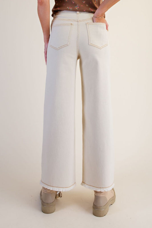 Back view of ecru straight-leg twill pants showing back pockets and frayed hems
