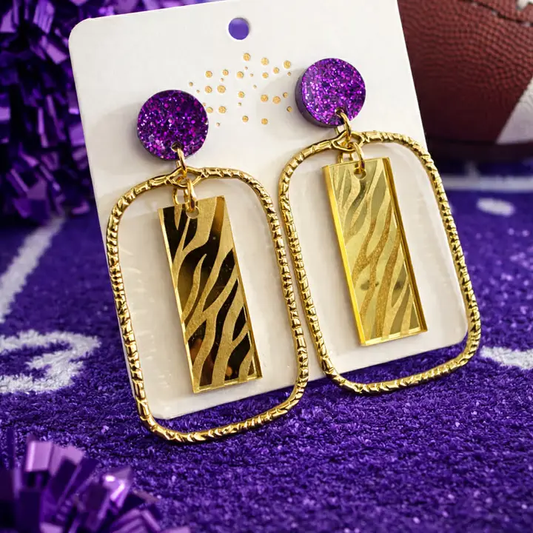 Tiger Glam earrings with purple sparkling studs, textured gold-tone open frames, and rectangular tiger-striped charms