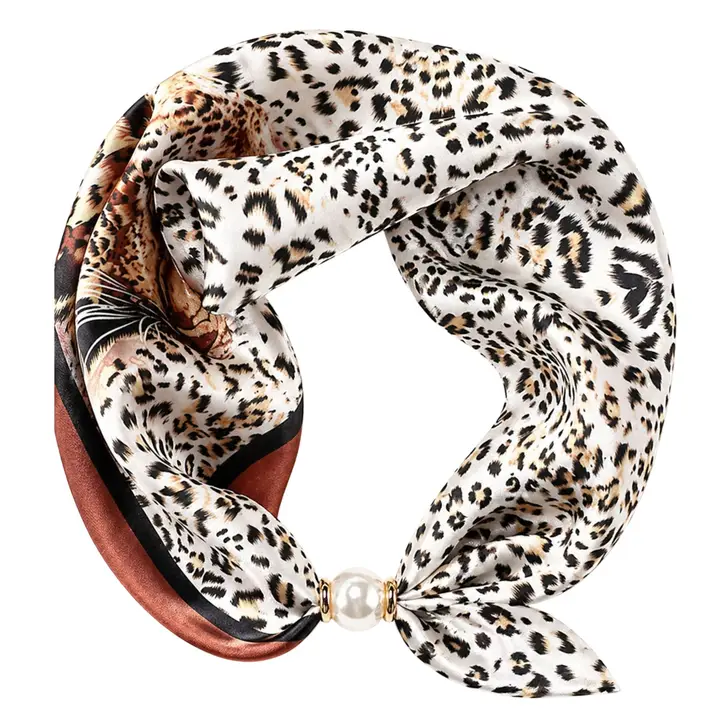 Ivory scarf necklace with black and warm-brown spotted print and a magnetic pearl closure, displayed against a white background.