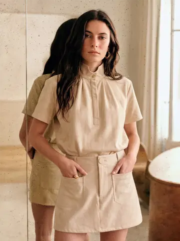 Model wearing the matching soft neutral stand-collar top and suede-look skort